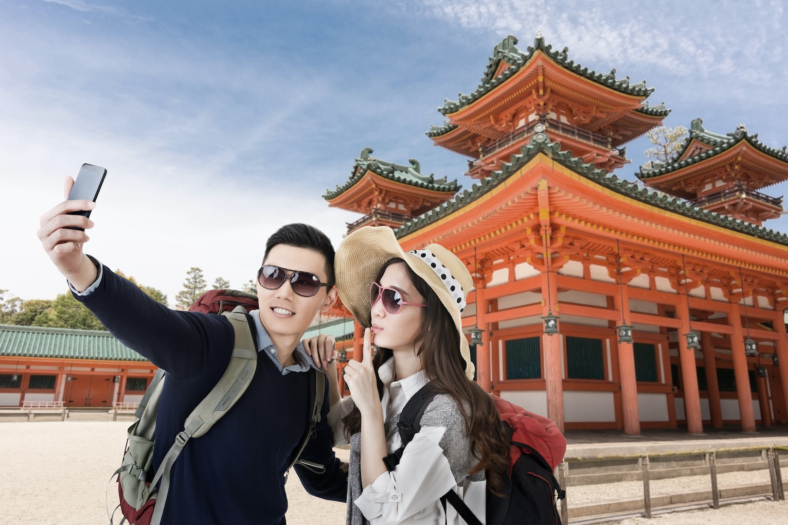 A young and fashionable Asian couple taking a selfie in front of the Heian Shrine, Kyoto, Japan.